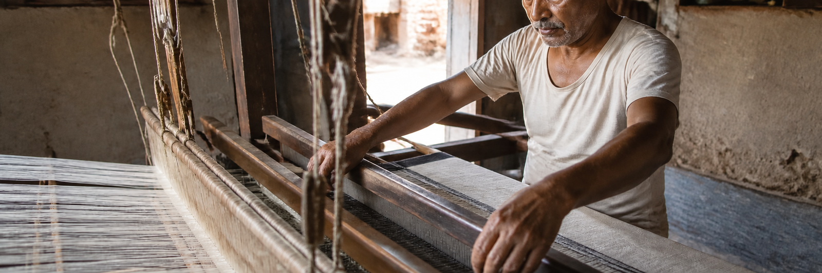 Generational weaver crafting cloth at traditional wooden pit-loom
